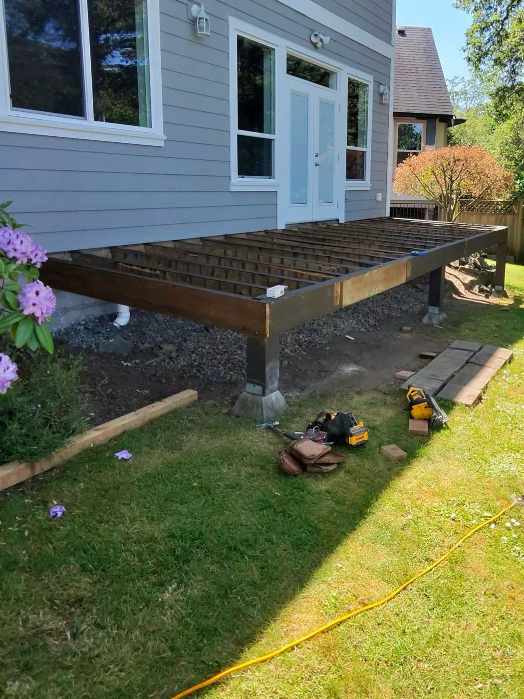 Deck framing on steel posts beside a house